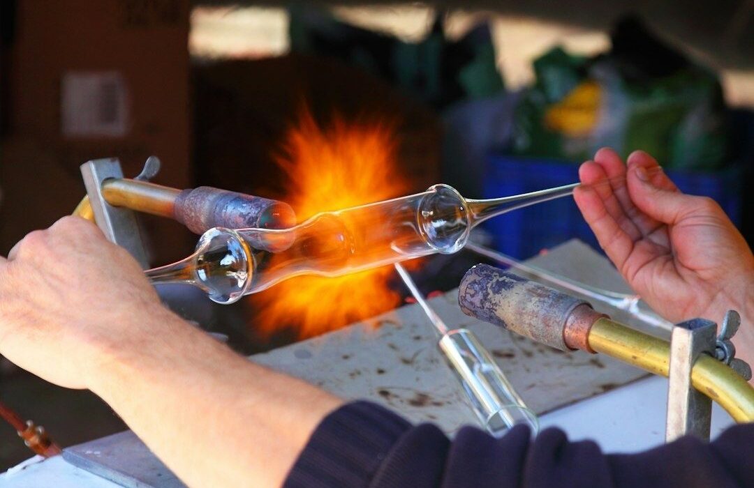 Souffleur façonnant du verre incandescent devant une flamme