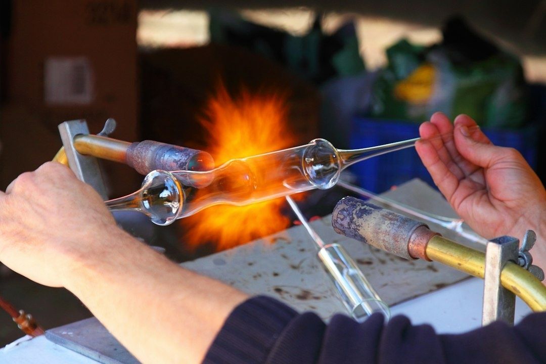 Souffleur façonnant du verre incandescent devant une flamme